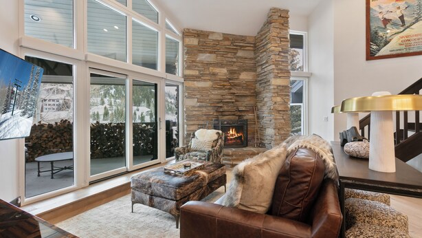 A spacious living room with a stone fireplace, leather furniture, and large windows. - Ski Retreat Hot Tub 2br + Loft 2 Bedroom Condo (Park City)