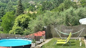 En trädgård med en pool, en hängmatta och en gul stol.