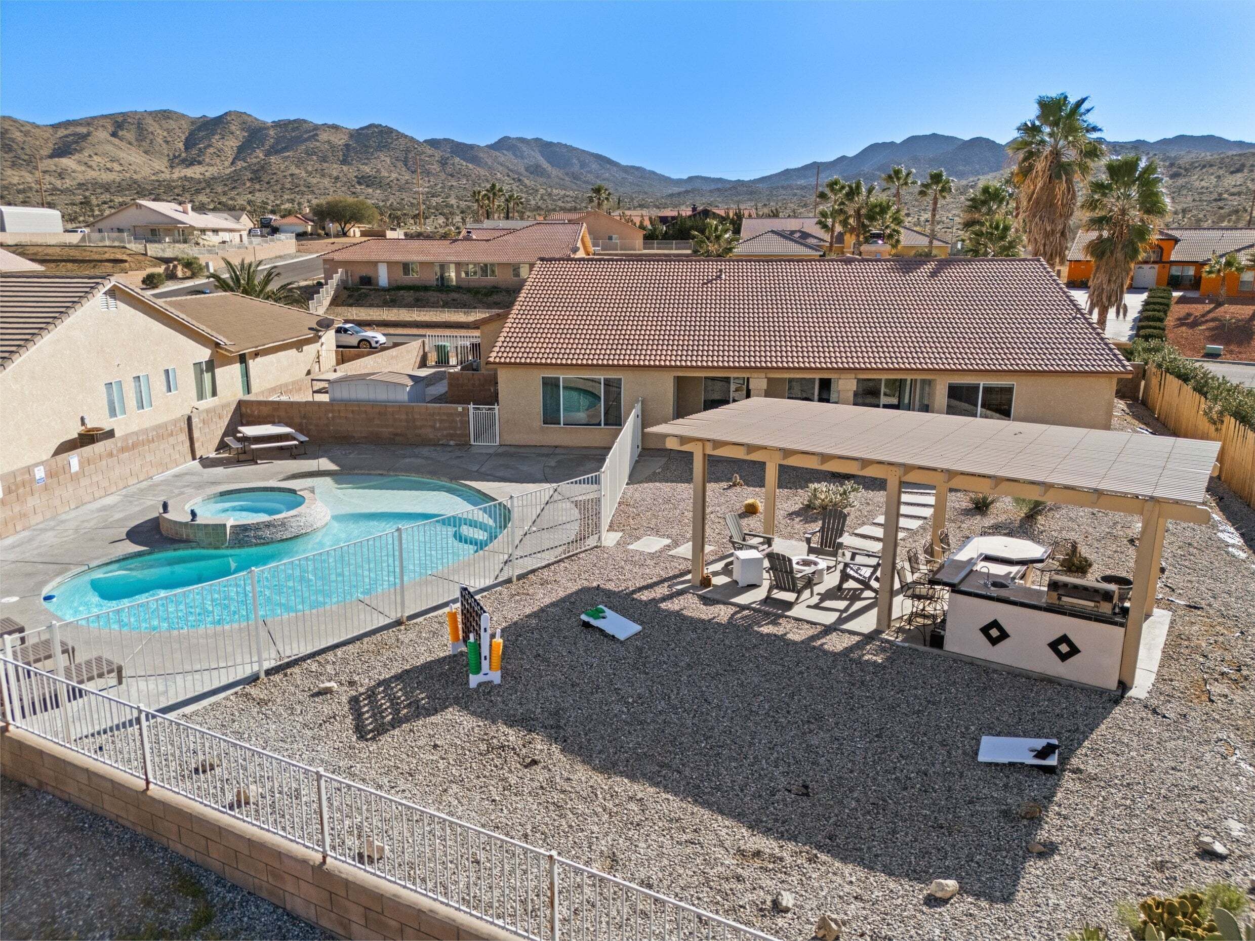 A residential area with a swimming pool, patio furniture, and a view of mountains.