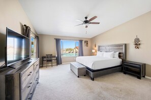 A hotel room with a bed, a TV, a desk, and a view of a swimming pool. - Casa Selecta - Pool, Hot Tub & Desert Skies 4 Bedroom Home (Yucca Valley)