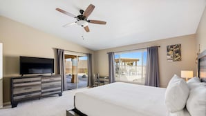 A hotel room with a bed, a TV, a ceiling fan, a desk, and a window with curtains.