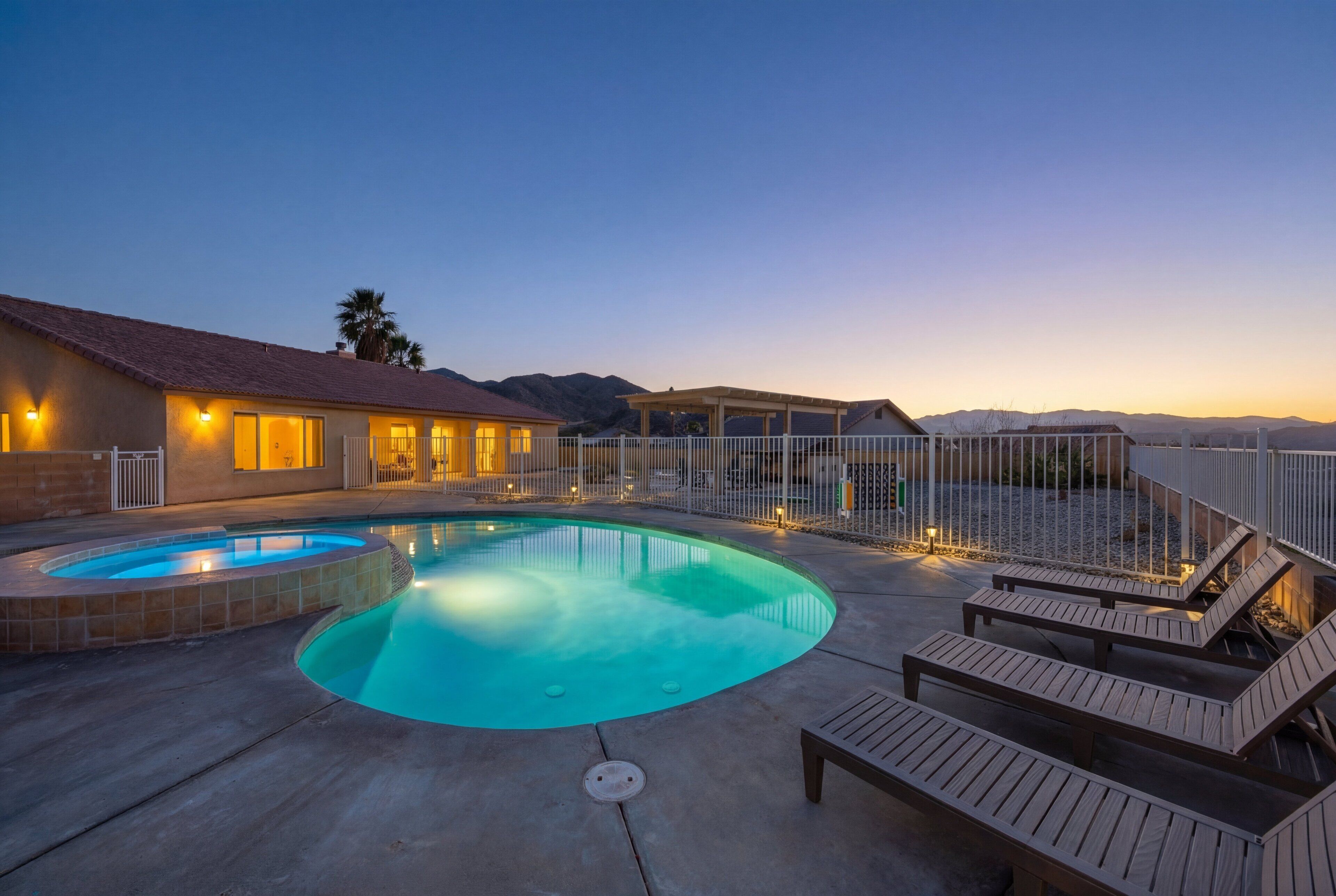 A swimming pool with lounge chairs and a house in the background.