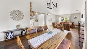 A spacious dining area with a wooden table, multiple chairs, and a chandelier.