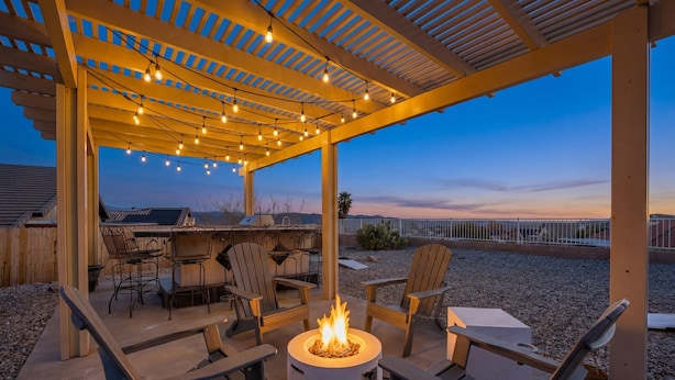 An outdoor patio with a fire pit, seating, and string lights.