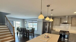 A modern kitchen with a central island, stainless steel appliances, and pendant lighting. - Cove Overlook Limit 6 3 Bedroom Home (Standish)