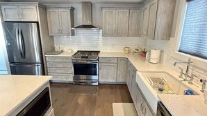A modern kitchen with stainless steel appliances, light wood cabinetry, and a large window providing natural light. - Cove Overlook Limit 6 3 Bedroom Home (Standish)
