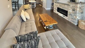 A modern living room with a large sofa, a wooden coffee table, and a stone fireplace. - Cove Overlook Limit 6 3 Bedroom Home (Standish)