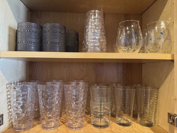 Una estantería de madera con varios vasos y tazas de vidrio.