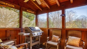 A cabin with a grill, two chairs with cushions, and large windows with 'CAMPING' signs. - Elk Crossing 3 Bedroom Cabin (Pigeon Forge)
