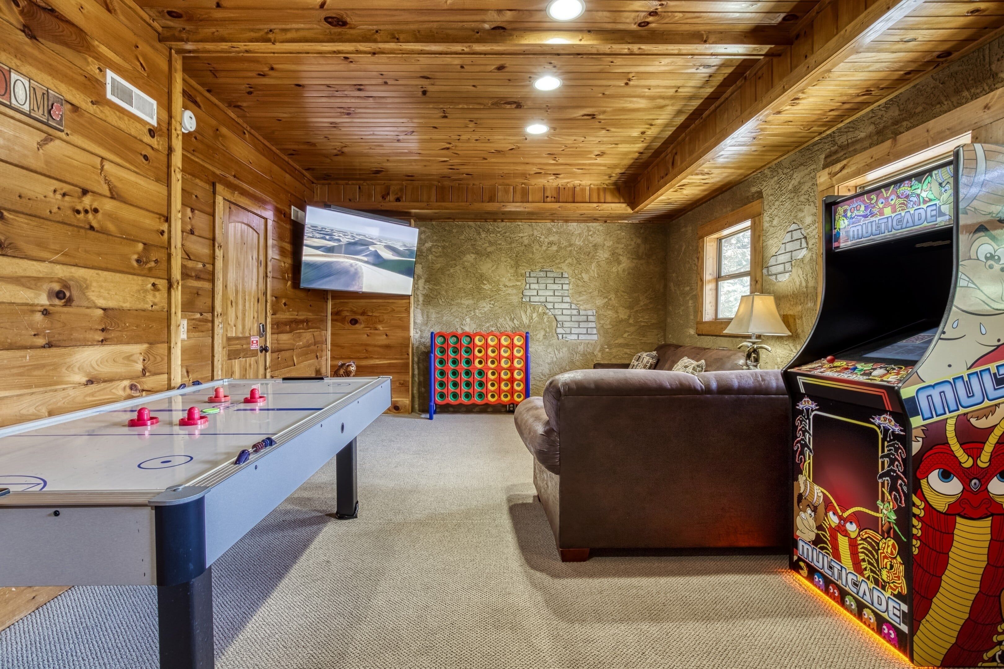 Una habitación con suelo de madera, una mesa de fútbol, un sofá, un televisor y una consola de videojuegos.
