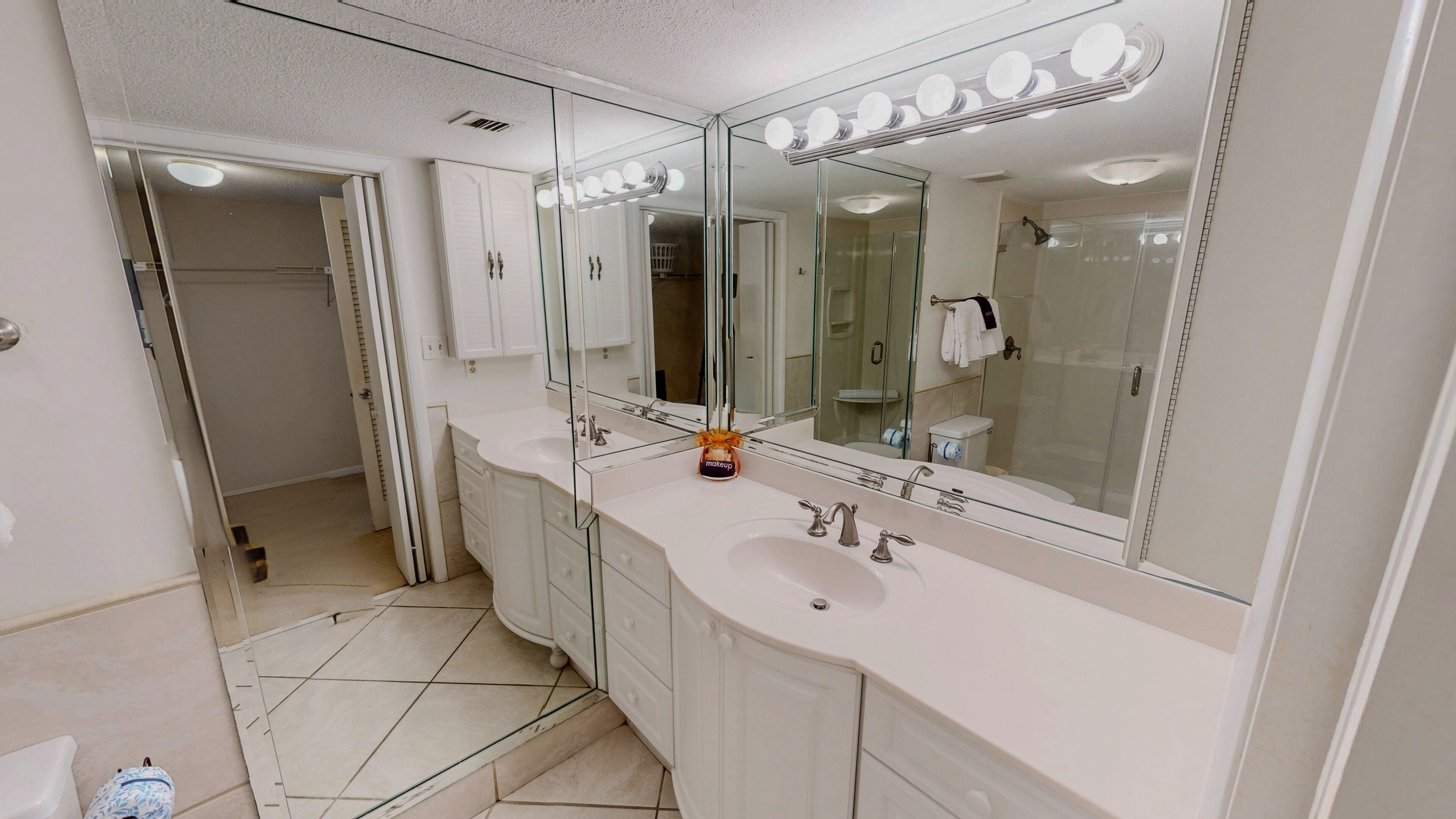 A modern bathroom with a large vanity, a double sink, and a walk-in shower.