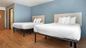 A hotel room with two beds, wooden flooring, and light blue walls. - Value Place Louisville Ky South (Fairdale)