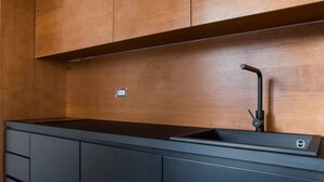 A modern kitchen with dark cabinetry, a black countertop, and a single faucet. - Weaver Suite Apartment By Dimorra  (Naples)