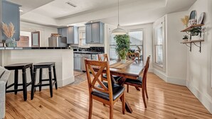 Une cuisine moderne avec des meubles de couleur grise, une table à manger en bois et des tabourets de bar.