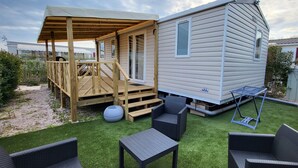 Une maison mobile dotée d’une terrasse en bois, d’un espace salon extérieur et d’une zone abritée.