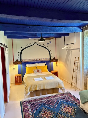 A bedroom with a bed, bedside lamps, a patterned rug, and a ladder against the wall. - La Grande Rossignol: Pool, spacious rooms, and private bathrooms in Occitanie. (Belvèze)