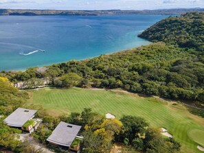 A golf course with a clubhouse and a view of the sea. - Casa Chorotega, an Iconic Five-Bedroom Retreat in Peninsula Papagayo (Peninsula Papagayo)