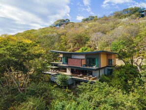 A modern two-story house with a flat roof, surrounded by dense forest. - Casa Chorotega, an Iconic Five-Bedroom Retreat in Peninsula Papagayo (Peninsula Papagayo)