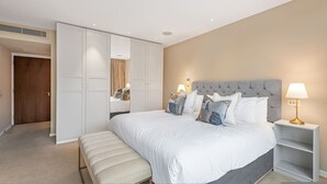 Ein Schlafzimmer mit einem großen Bett, einer Bank, einem Nachttisch und einem Kleiderschrank.