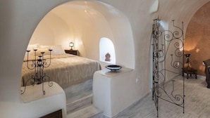 Un dormitorio acogedor de arcos, con cama, mesita de noche y detalles de metal decorativo.