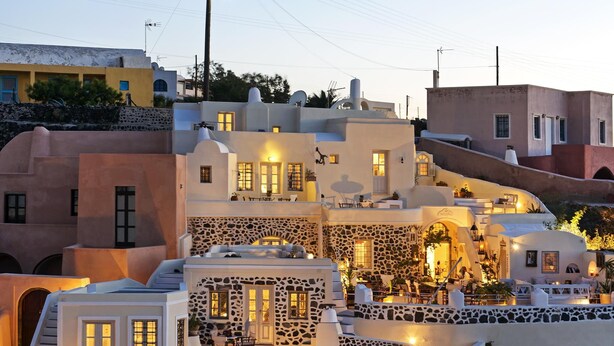 Un edificio de varios pisos con fachada de piedra, varios balcones y zonas de estar al aire libre.