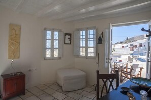Ein Zimmer mit einem kleinen Tisch, einer Bank und einem Fenster mit schmiedeeisernen Gitterstäben.