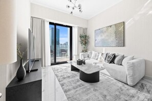 A modern living room with a sofa, coffee table, and a large window with a city view. - Bloomfields Luxurious 3Br in Al Maryah V (Abu Dhabi)