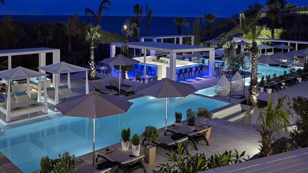 A pool area with lounge chairs, umbrellas, and a bar. - Aurora Luxury Hotel & Spa (Santorini)