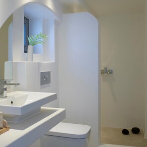 A modern bathroom with a white sink, mirror, and toilet. - Aurora Luxury Hotel & Spa (Santorini)