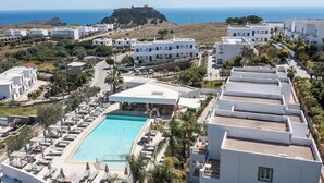 Un resort con piscina, edificios blancos y vista al mar.