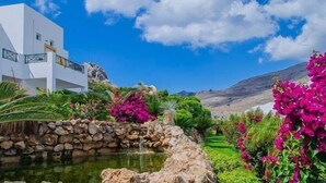 Un edificio blanco con un muro de piedra y una pequeña fuente.