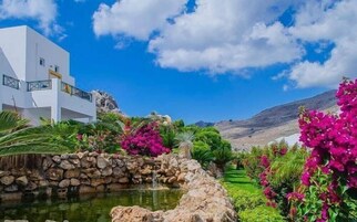 Un edificio blanco con un muro de piedra y una pequeña fuente.