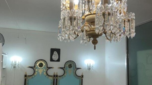 Une chambre à coucher avec un grand lit, une tête de lit décorée et un lustre.