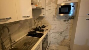 Une cuisine compacte équipée d’un four à micro-ondes encastré, d’une plaque de cuisson et d’un évier.