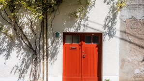 Una puerta roja con una ventana, base de piedra y un letrero en la pared.