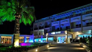Een hotelentree met een palmboom, een fontein en een bordje met de tekst 'Sea Melody'.