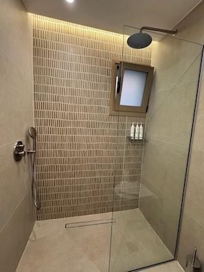 A modern shower with a glass door, a handheld showerhead, and a wall-mounted control panel. - The Noverian Antama Organic Beach Resort Chania (Chania)