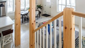 A spacious loft with a high ceiling, wooden beams, a staircase with a wooden railing, and a dining area with a table and chairs. - Lakefront with Private Dock & Canoe Kenoza Den (Jeffersonville)