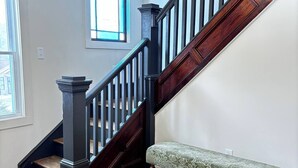 A wooden staircase with a dark finish, a bench with a patterned cushion, and a window with a view of the outside. - Kenoza House with Private Lake and Kayaks (Callicoon)