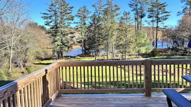A wooden deck with a railing overlooking a grassy area with trees and a lake. - Kenoza House with Private Lake and Kayaks (Callicoon)