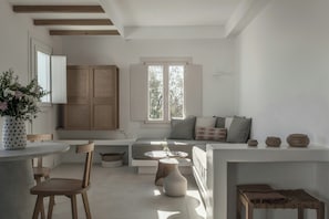 Un interior moderno con zona de comedor, sofá y ventana que deja entrar luz natural.