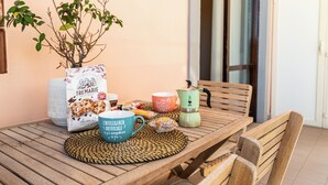 A wooden table with a woven placemat, a coffee pot, a blue mug, a bag of cookies, and a potted plant. - Cozy and modern apartment in the most elegant neighborhood of Naples (Napoli)
