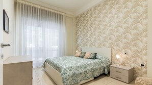 A bedroom with a bed, bedside table, and a nightstand. - Cozy and modern apartment in the most elegant neighborhood of Naples (Napoli)