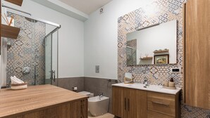A modern bathroom with a wooden vanity, a large mirror, and patterned tiles. - Cozy and modern apartment in the most elegant neighborhood of Naples (Napoli)