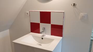 A bathroom with a white sink, red and white tiled backsplash, and a mirror.