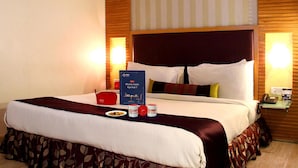 Une chambre d’hôtel avec un grand lit, une table de chevet avec une lampe et une petite table de nuit avec un téléphone.