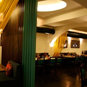 A restaurant with a long table, chairs, and a green curtain. - OYO Premium Karkhana Secunderabad (Hyderabad)