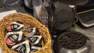 Een koffiezetapparaat, een mand met koffiecups en een Tassimo houder op een aanrecht.