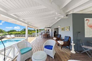 Un espace extérieur abrité comprenant une piscine, des meubles en osier et une table à manger.