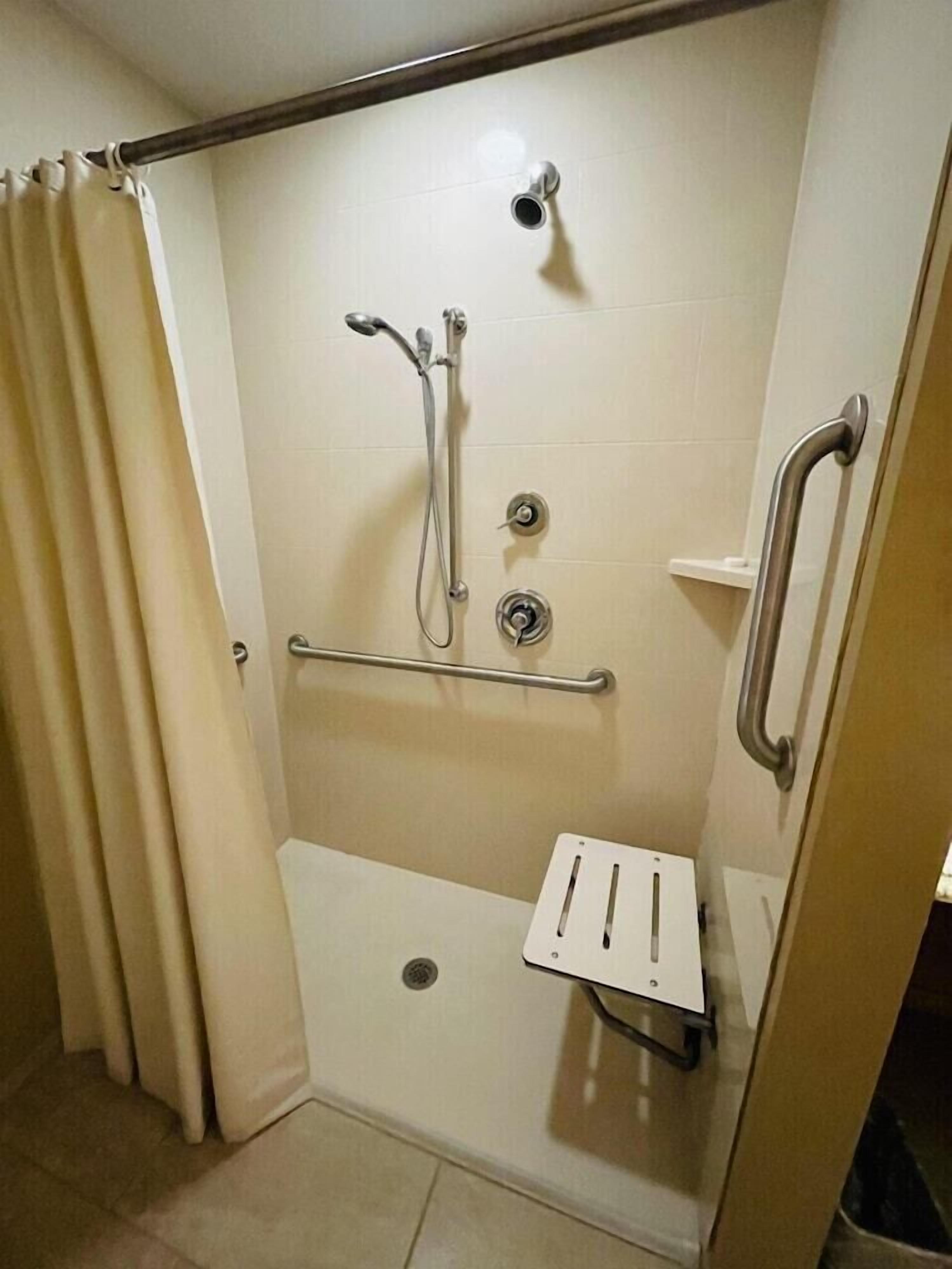 Ducha con barra de apoyo, cabezal de ducha de mano y panel de control.